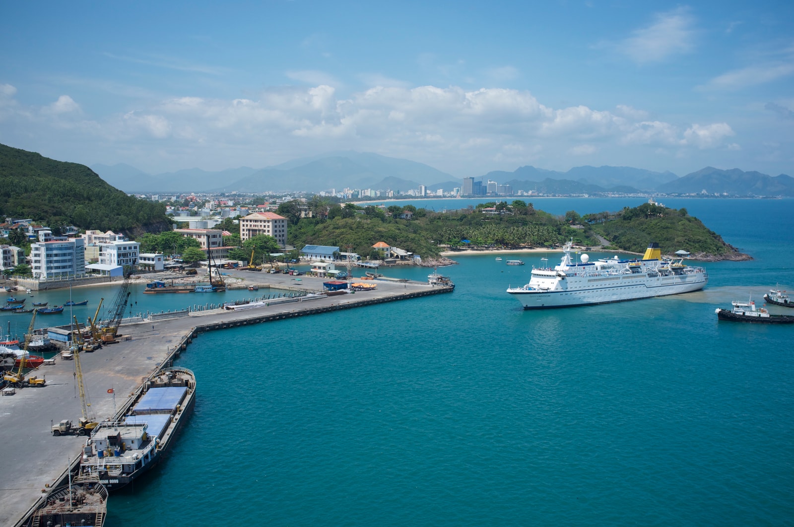 A panoramic view of Nha Trang's harbor, filled with boats on turquoise water under a clear sky.