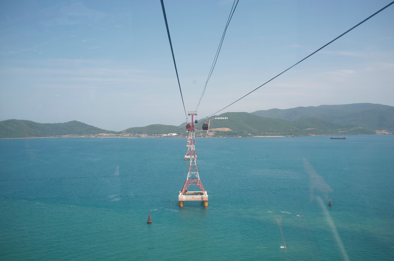 A clear view of the Vinpearl cable car line and a support tower over turquoise water.