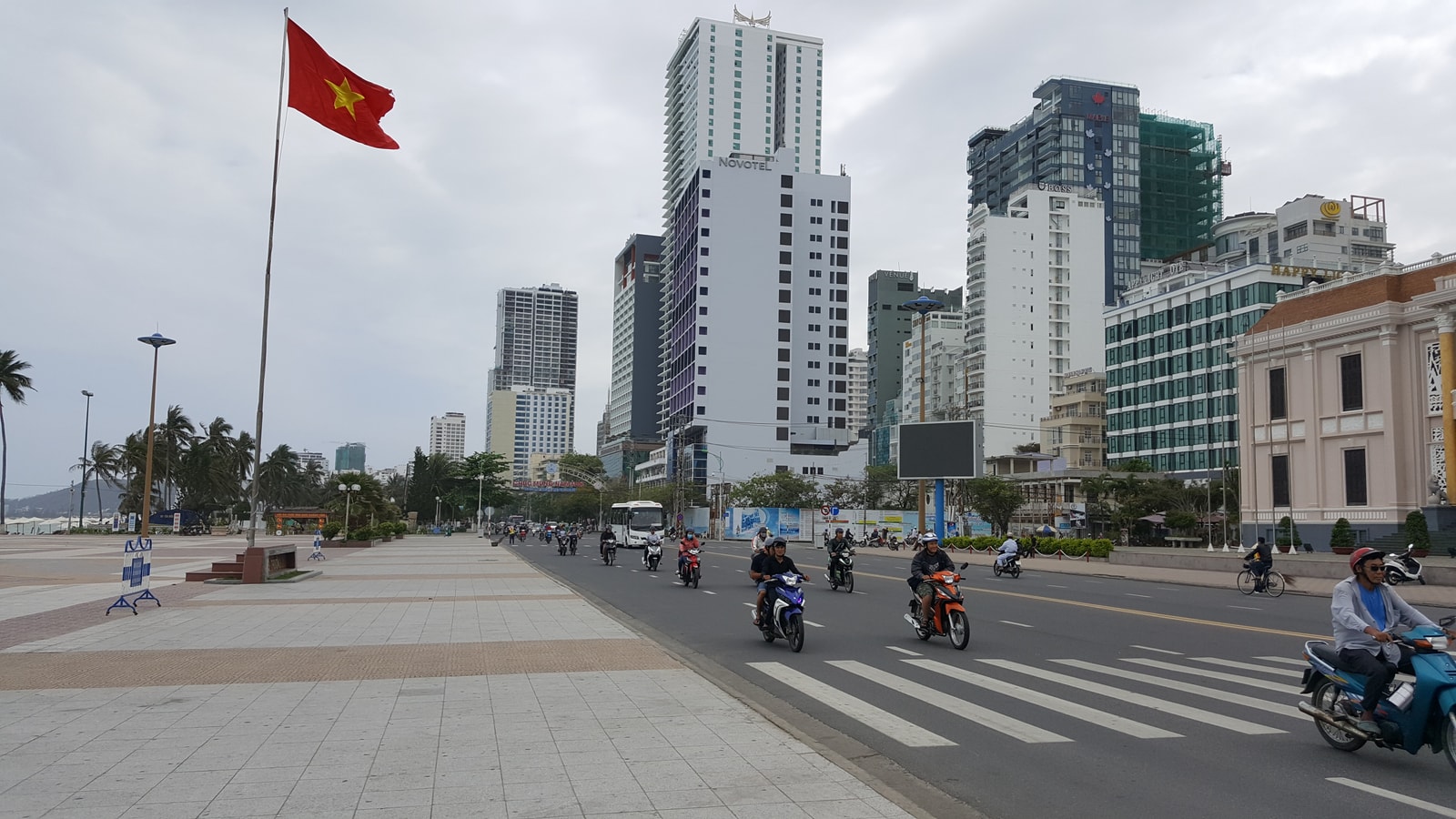 A wide promenade next to a busy street, with the beach and ocean visible on the right.