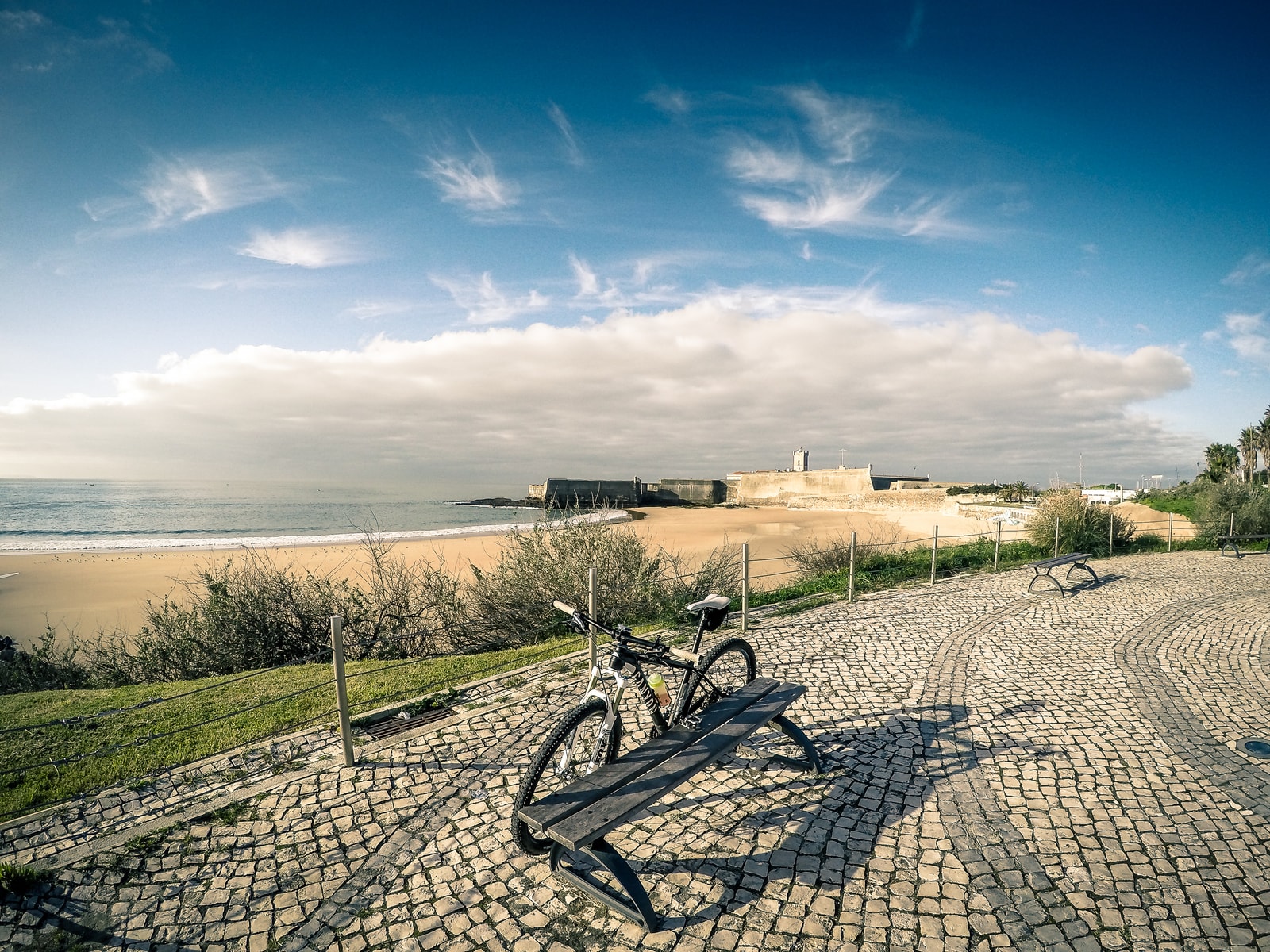 The golden sands of Praia da Torre framing the massive historic fortress of Sao Joao da Barra in Oeiras