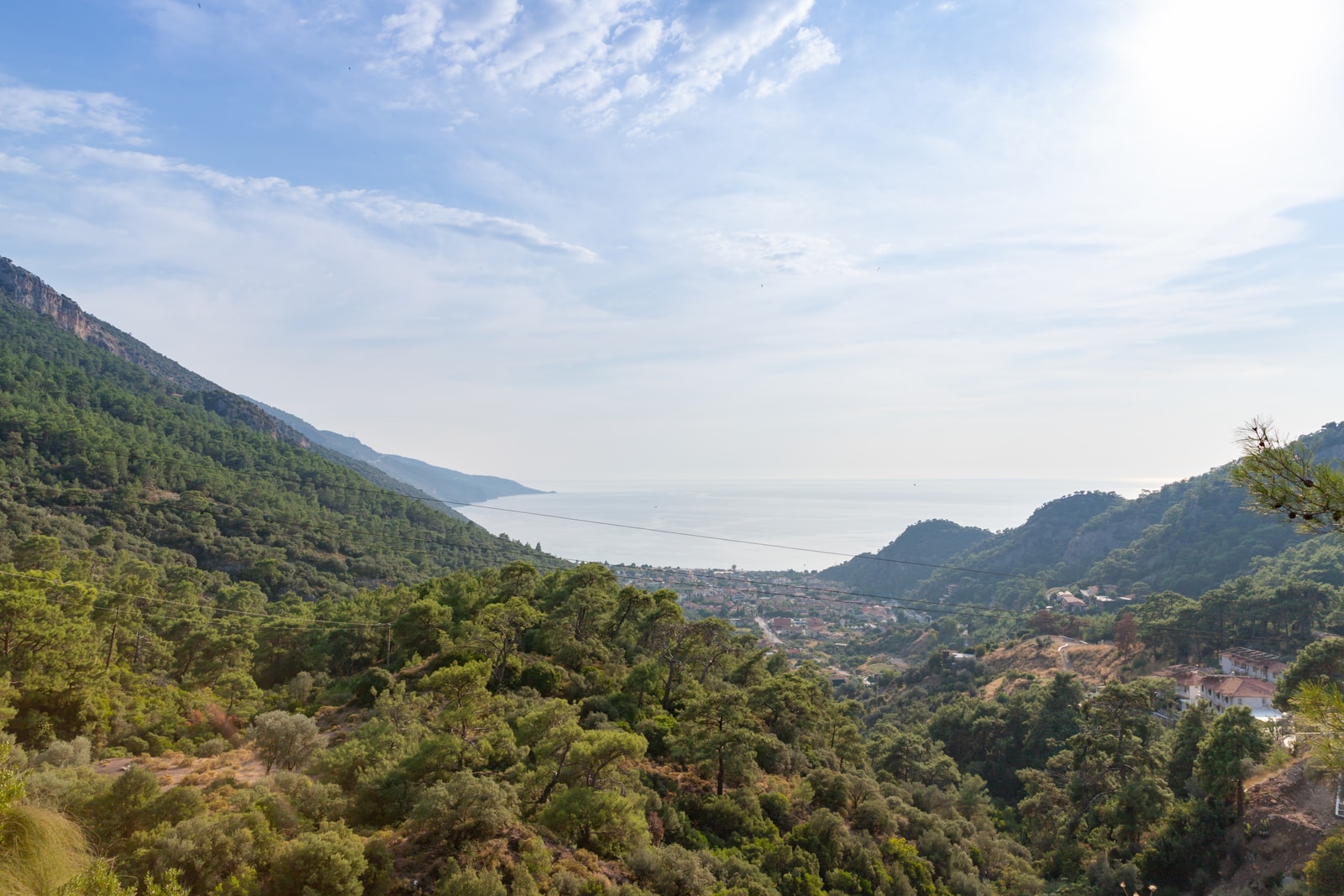 A view from a vegetated hillside looking down onto Ölüdeniz bay and the open sea beyond.