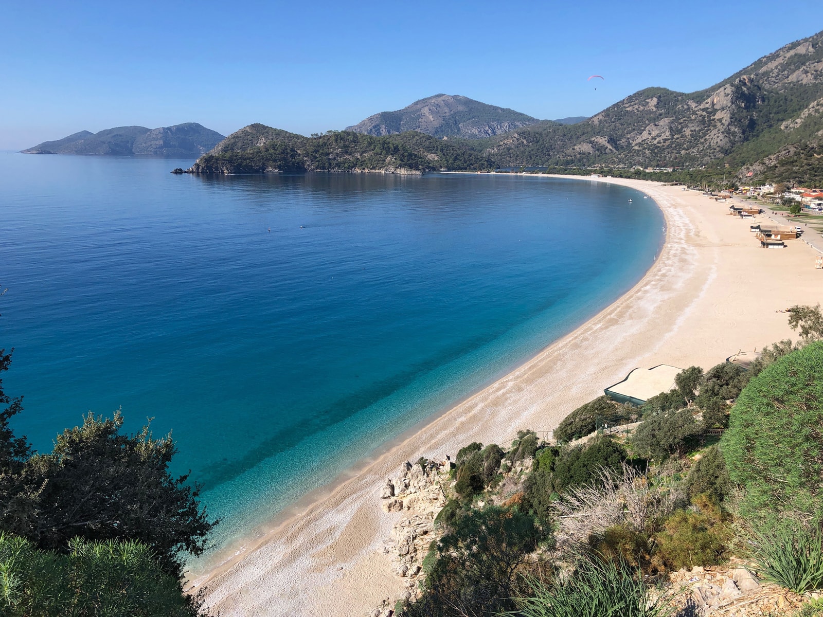 The curved bay of Ölüdeniz seen in the soft morning light, with mountains rising in the background.