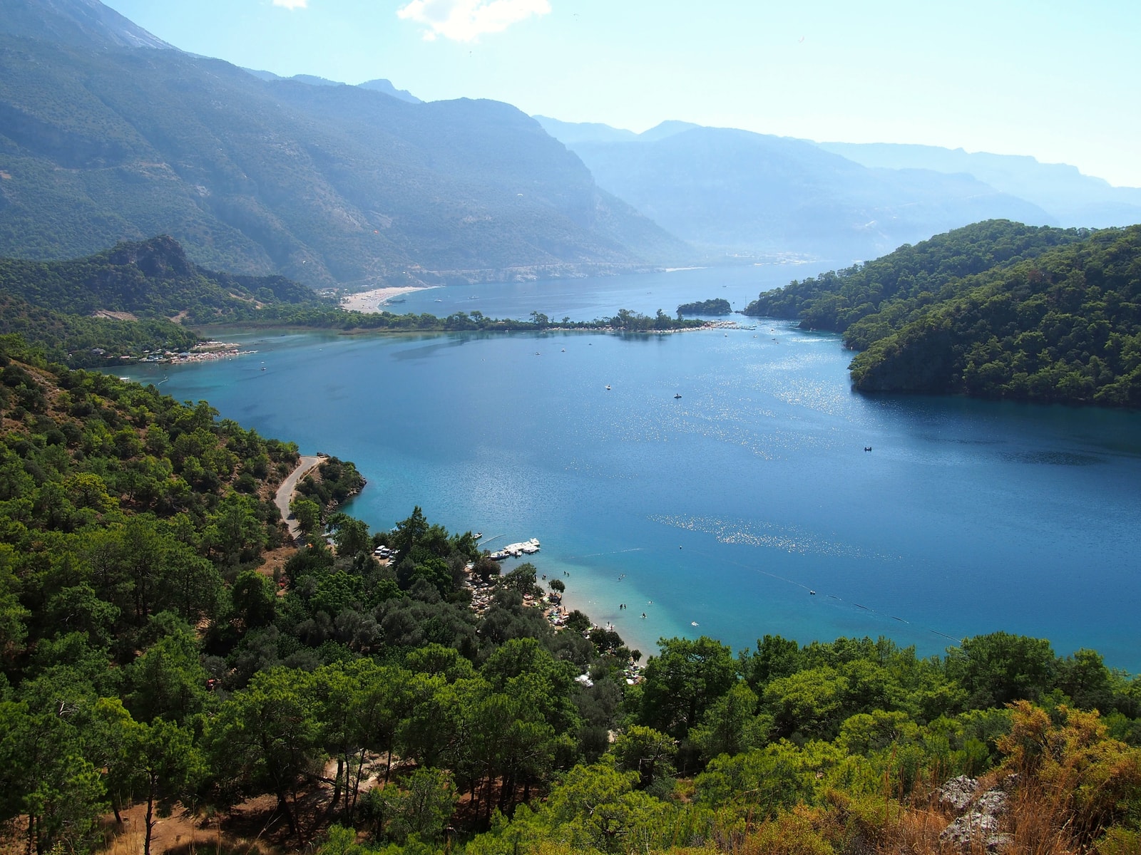 A panoramic view of the Blue Lagoon, showing its calm, turquoise waters enclosed by green, wooded hills.