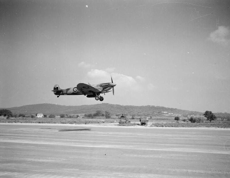 An archival black-and-white photo from 1944 showing an RAF Spitfire landing on a strip at Ramatuelle during Operation Dragoon.
