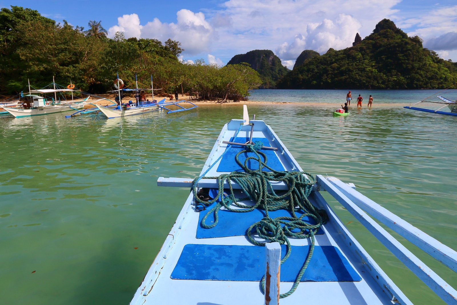 An outrigger boat, known as a bangka, approaches the white sandbar of Snake Island in Palawan.
