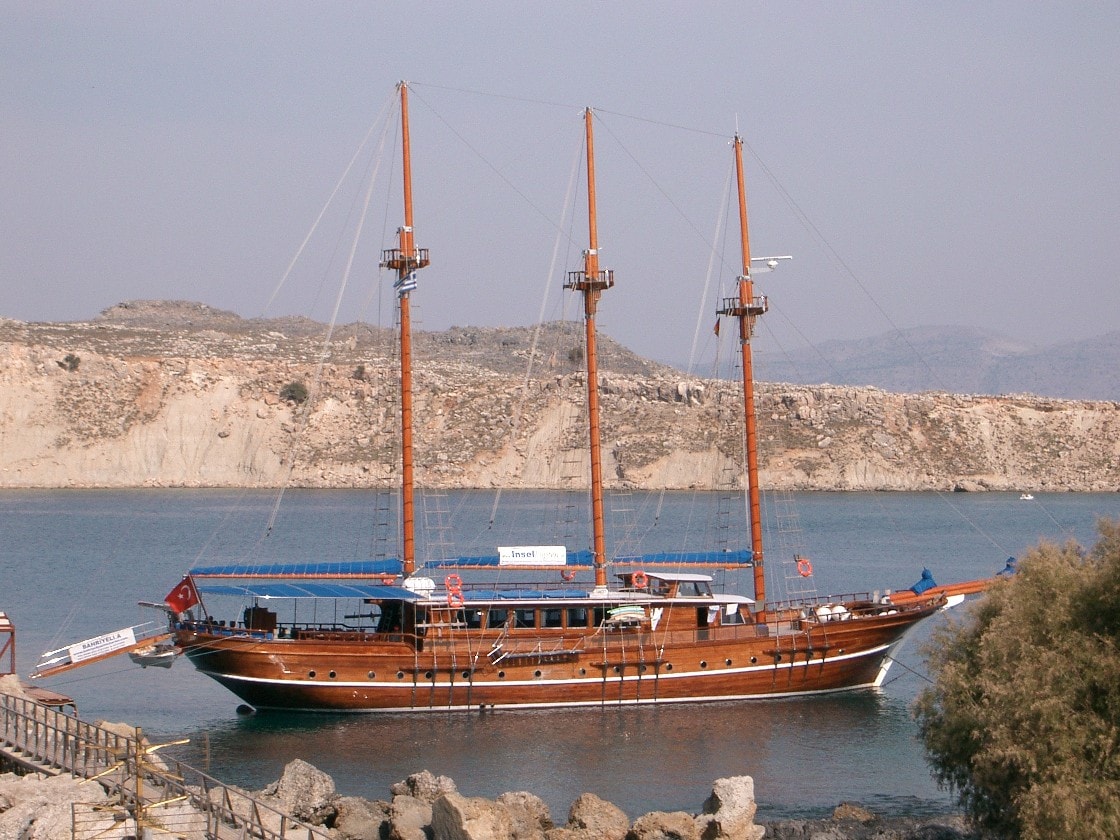 A traditional wooden boat is moored at a small pier on Pallas Beach, ready for excursions.