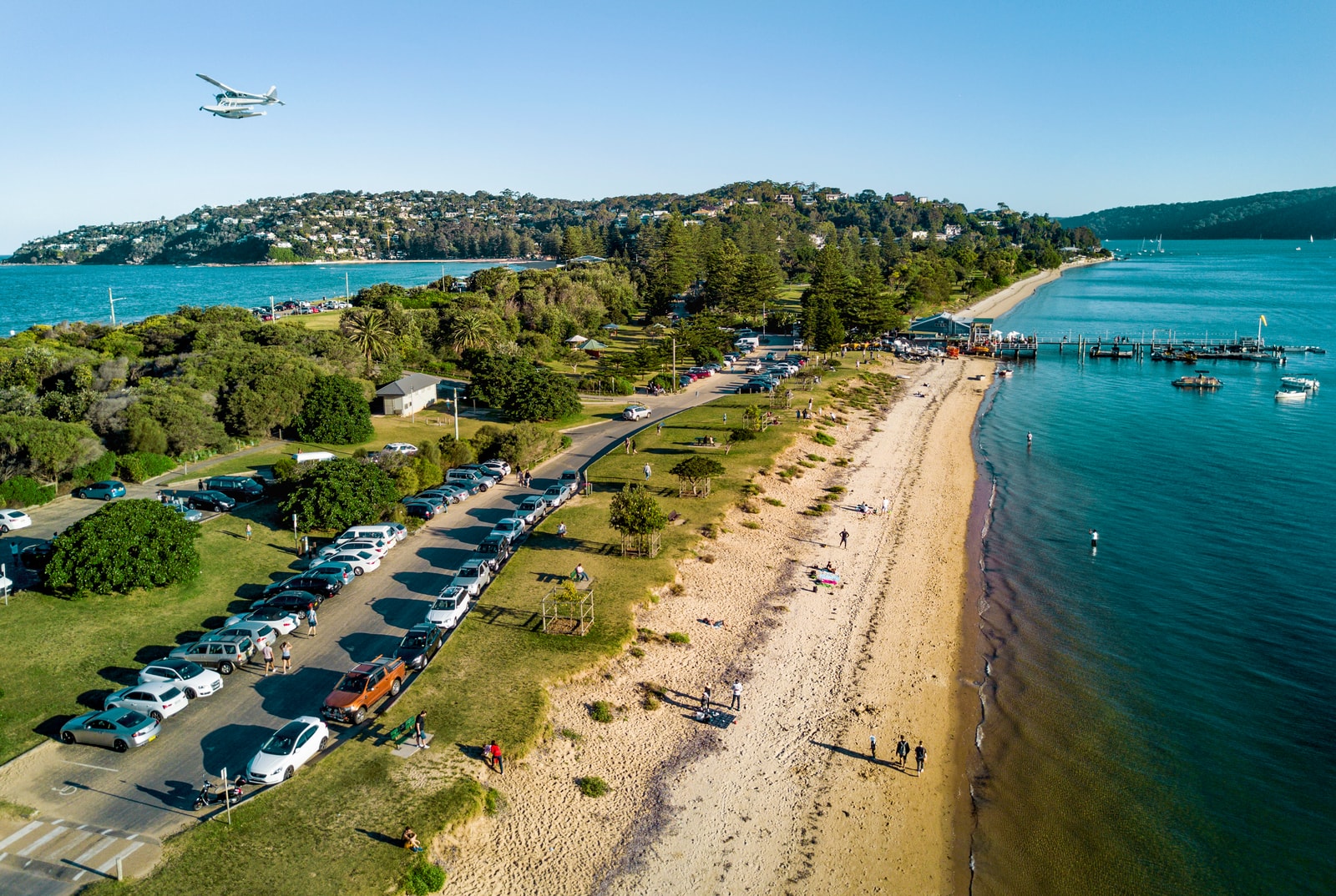A stunning aerial photograph captures the length of Palm Beach, with its narrow strip of land separating the turquoise ocean from the calm waters on the other side.