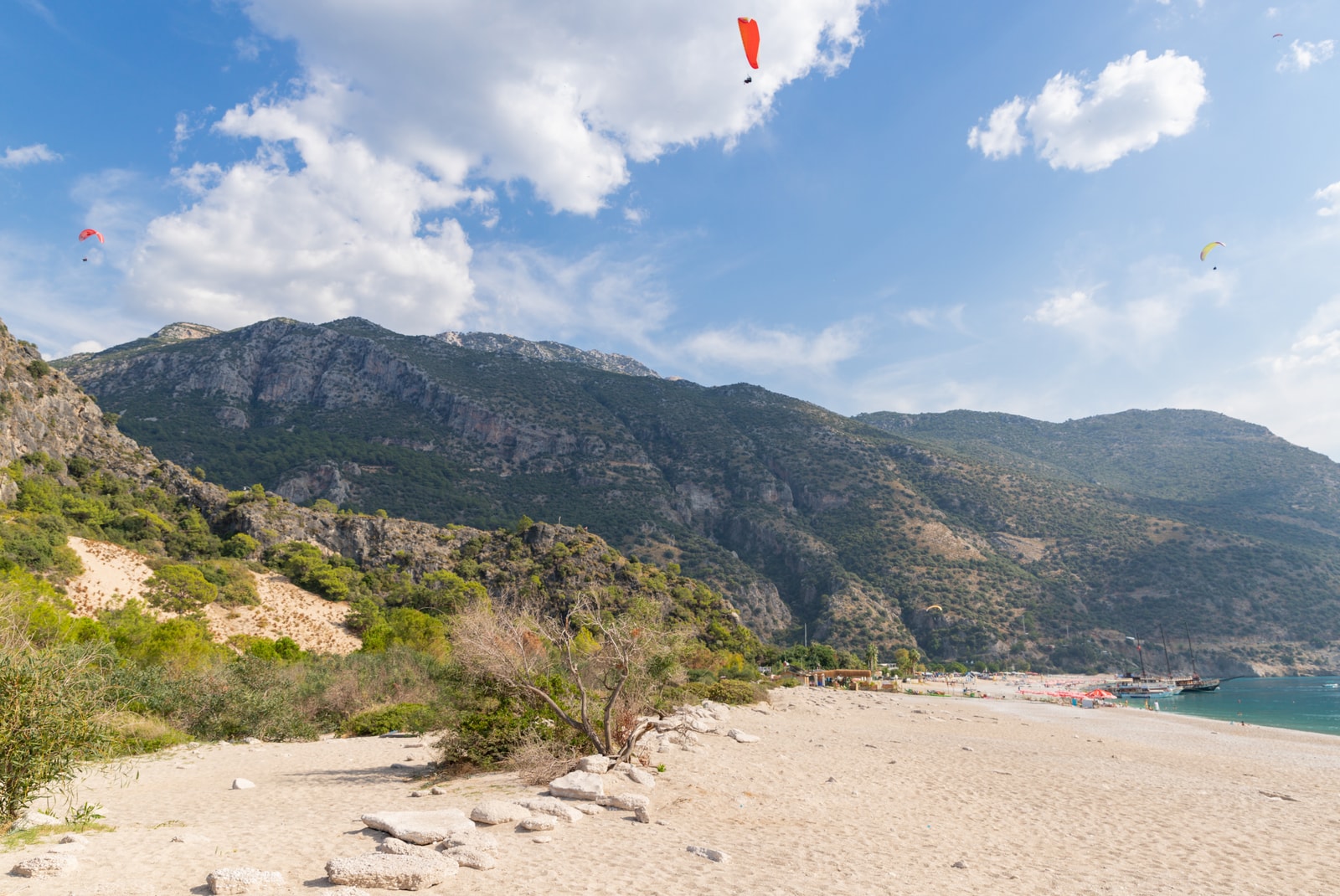 A paraglider flies over the crescent-shaped beach and turquoise lagoon of Ölüdeniz.