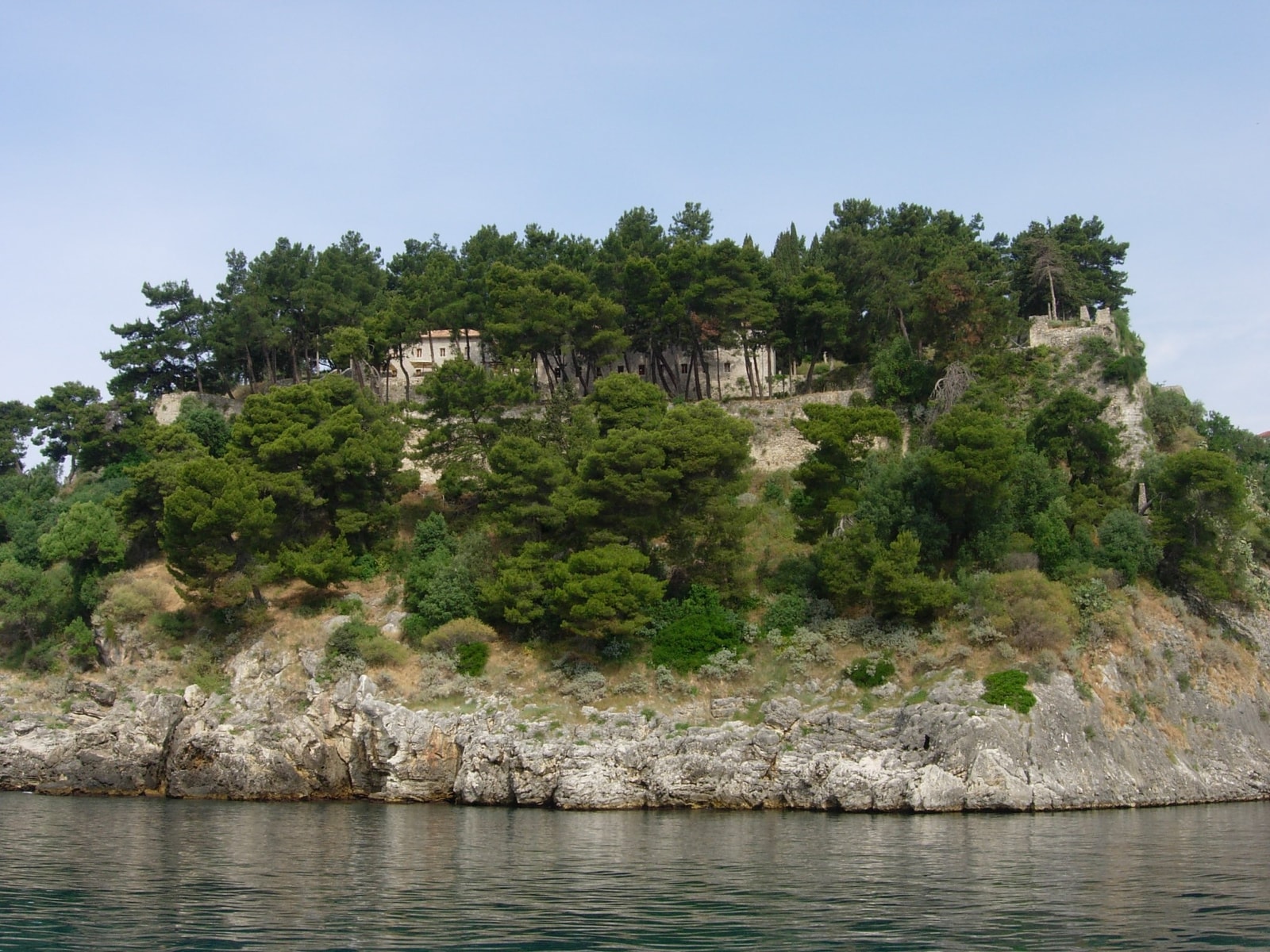 The stone walls of Parga's castle sit atop a steep, pine-covered cliff plunging into the sea.