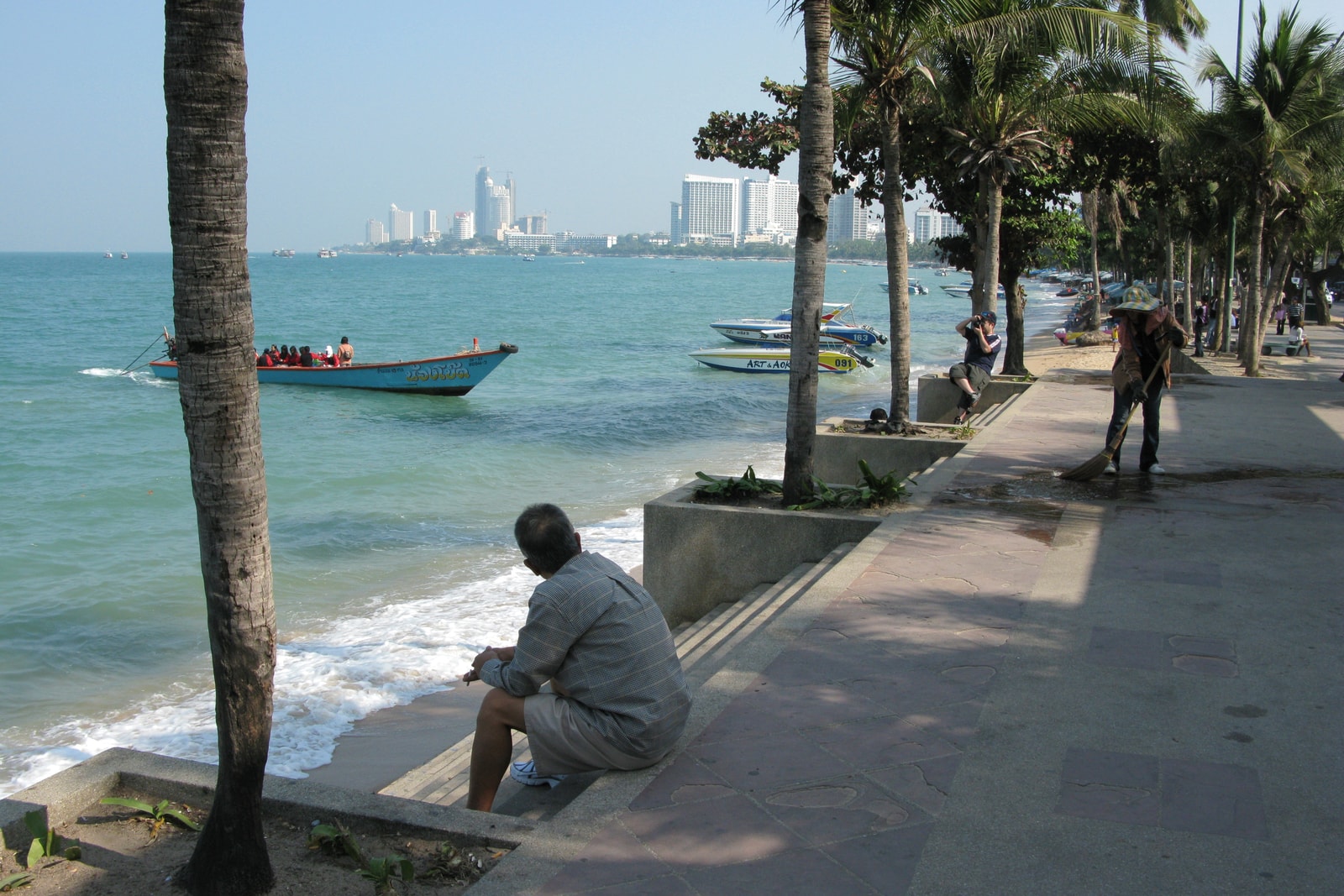 A view of Beach Road in Pattaya, with its palm-tree-lined promenade on one side and the city's hotels and shops on the other.