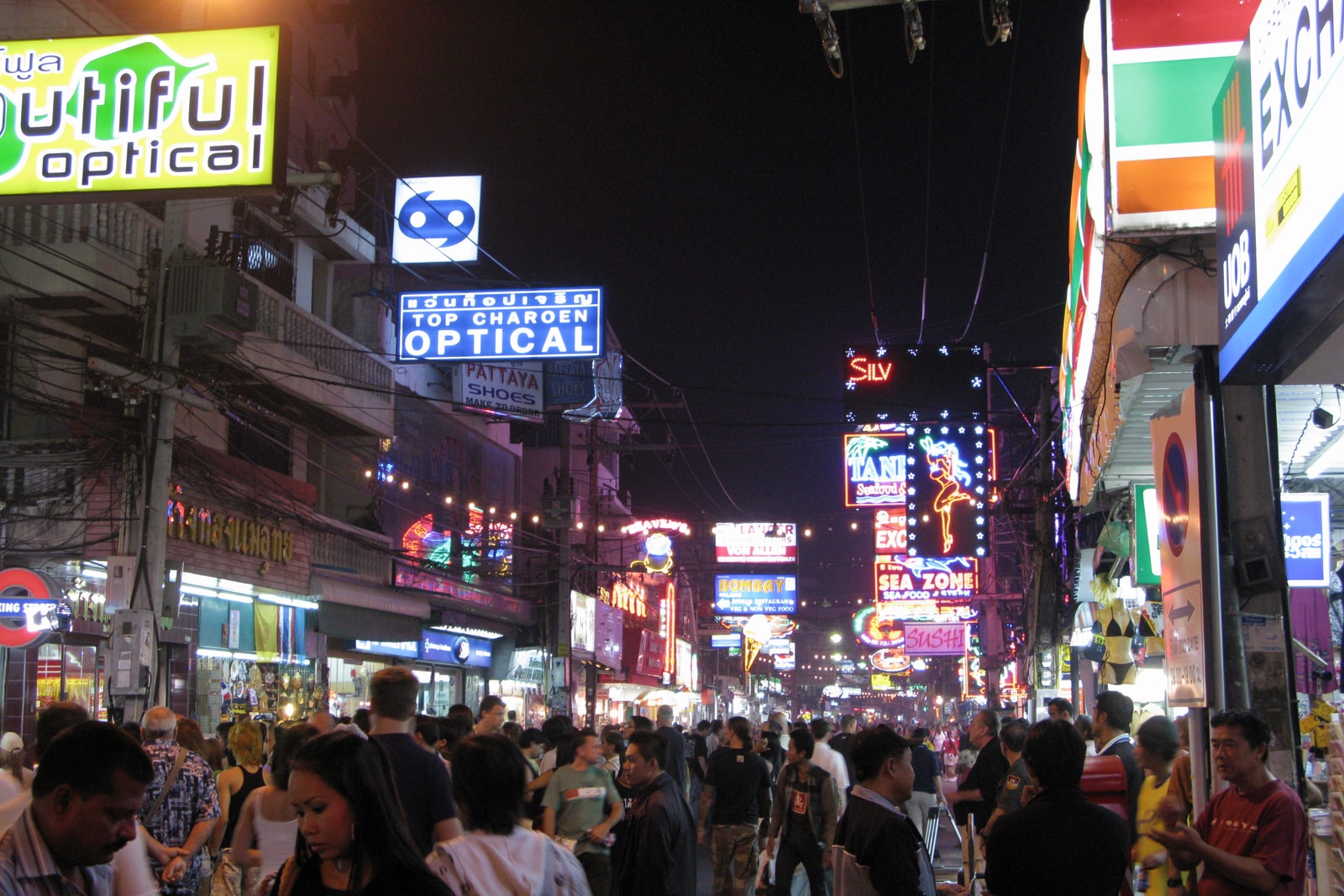 A vibrant night scene on Walking Street in Pattaya, with bright neon signs illuminating the crowded street.