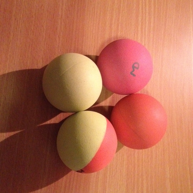 Close-up photograph of four custom-made, hand-sanded 'balun' rubber ball cores resting on wood.