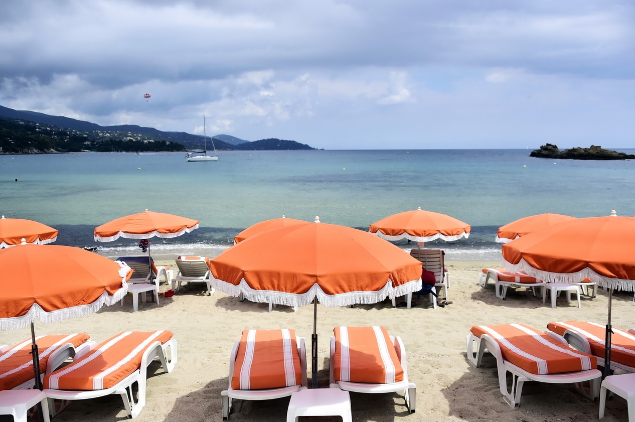 Rows of bright orange beach umbrellas and sun loungers on Plage de Saint-Clair.