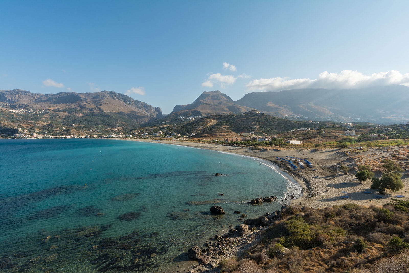 Clear turquoise water on a Cretan beach with a rocky foreground