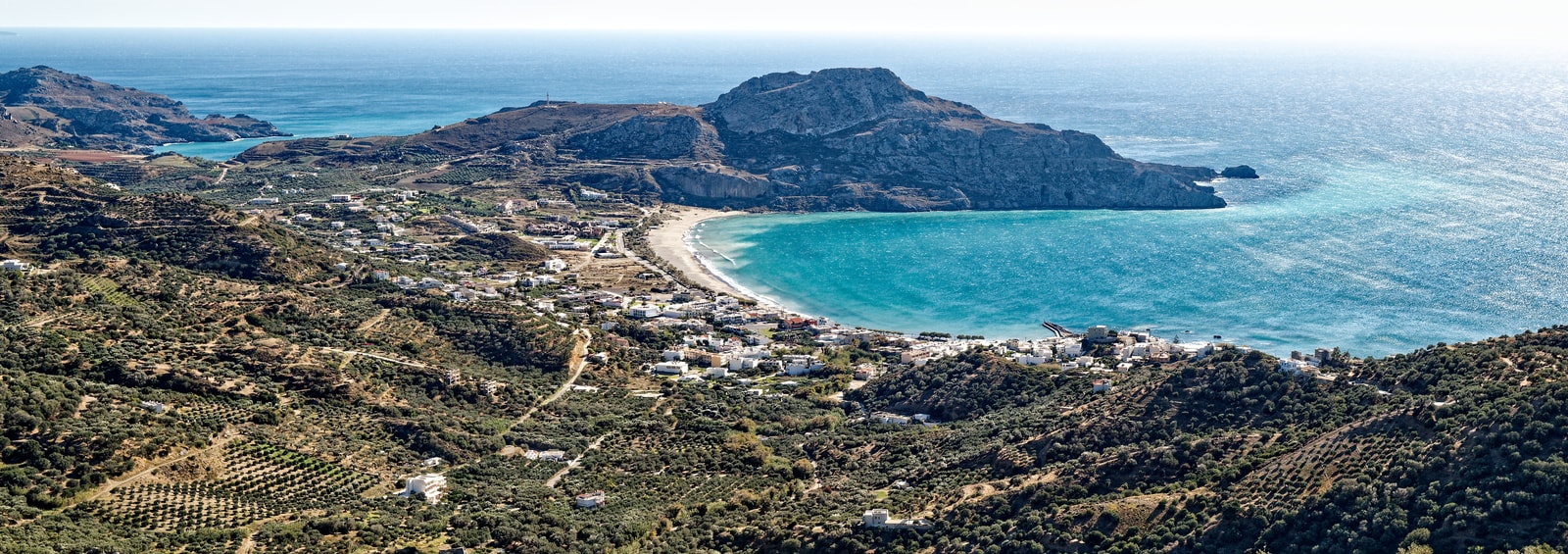A wide panorama shows the bay of Plakias backed by dramatic mountains