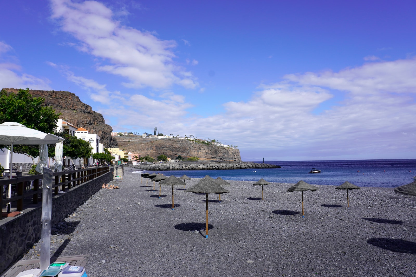 A beach-level view of Playa de Santiago, showing the dark pebbles, the sea, and a rugged headland.
