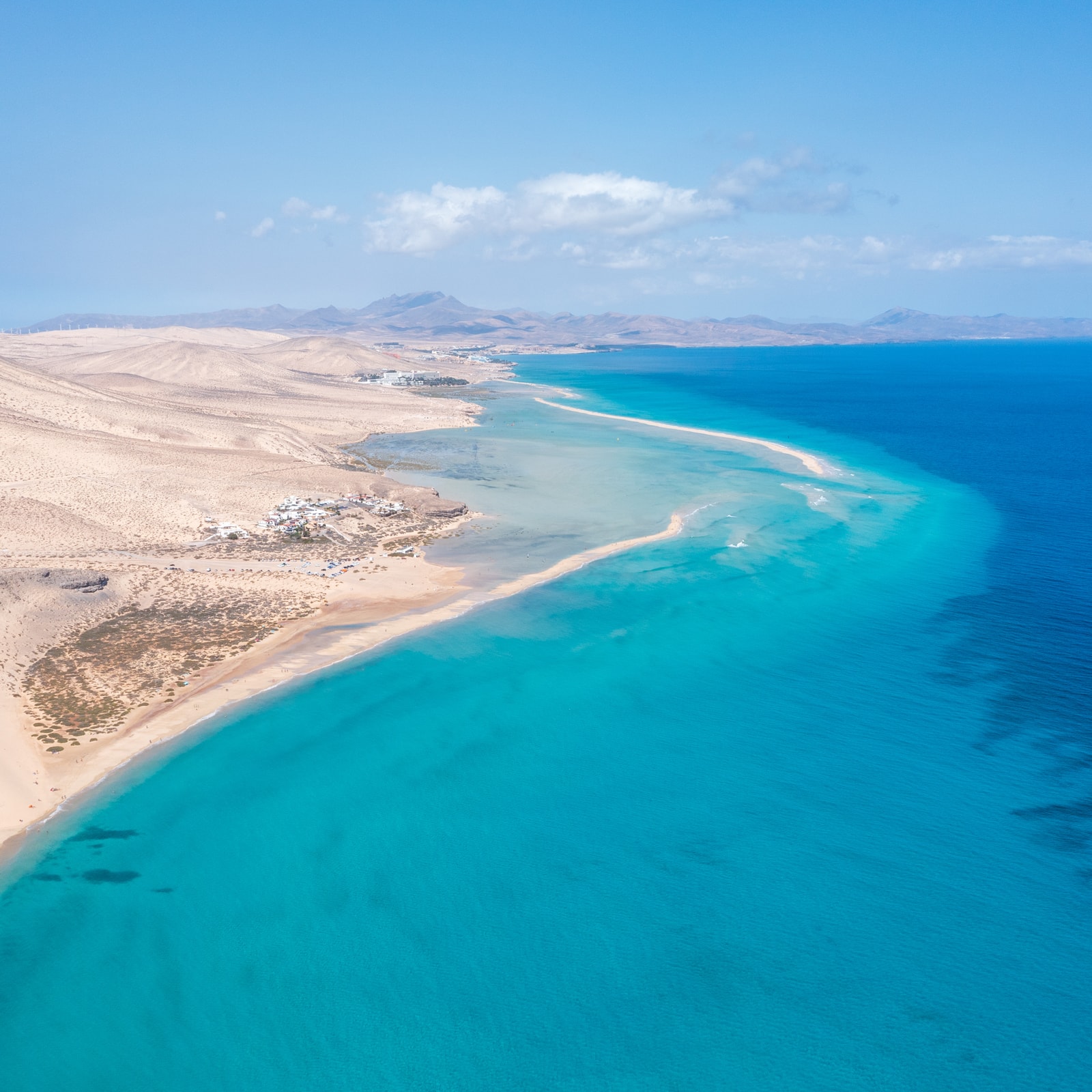 An aerial square shot of Sotavento's tidal lagoon, showing a stunning gradient of turquoise water, white sandbars, and the deep blue ocean.