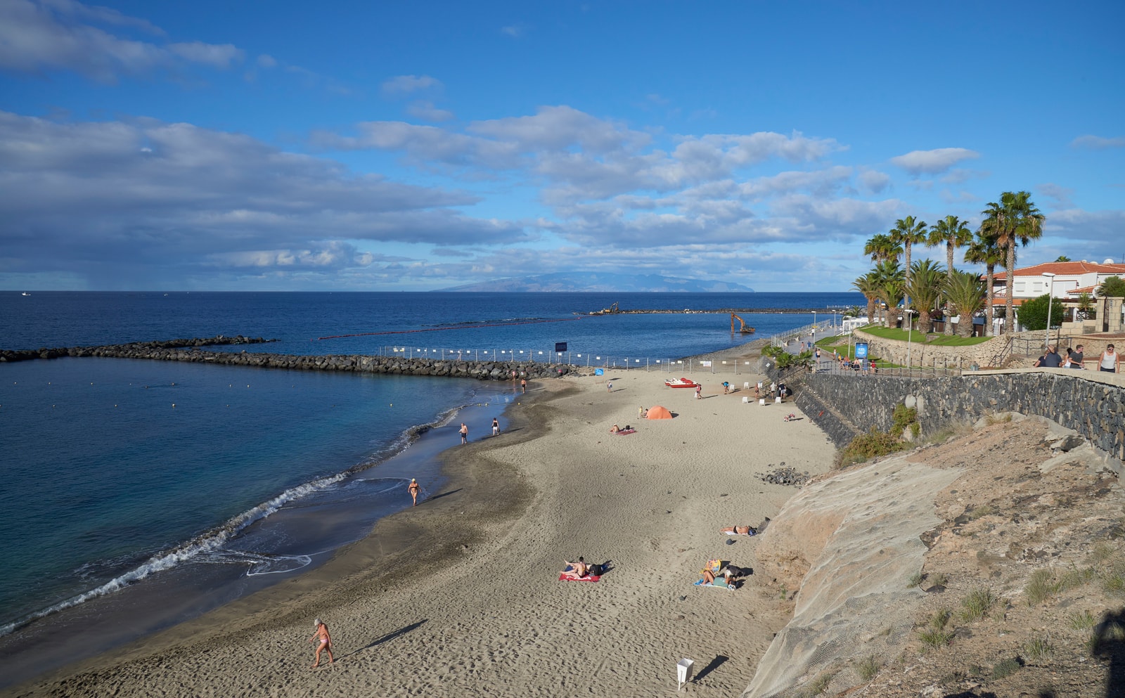 A sheltered beach along the Adeje coast, with calm water protected by volcanic rock breakwaters.