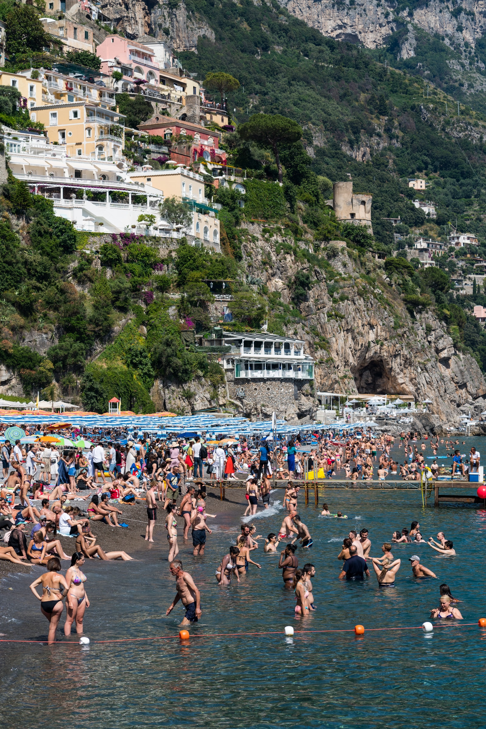 An elevated view of Positano's crowded main beach and cliffside homes.