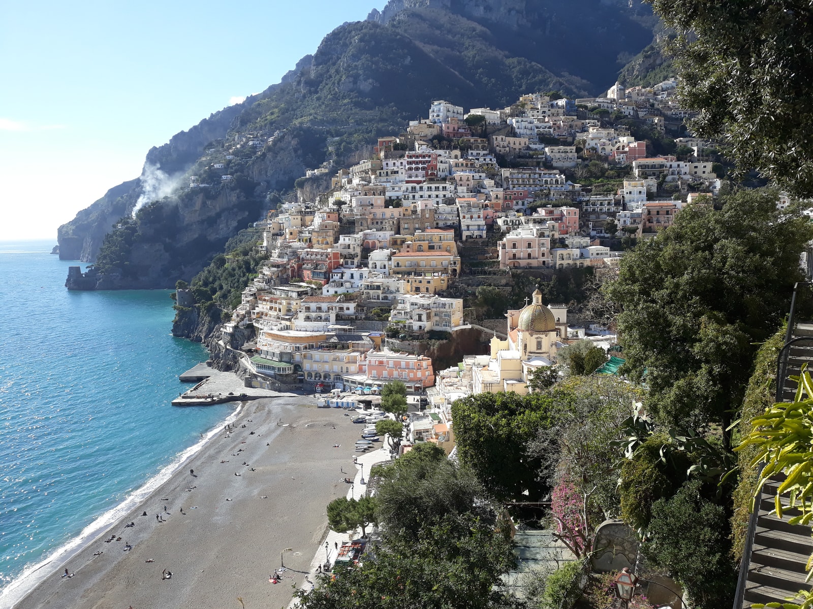 Positano's beach viewed from a stairway, with the domed church prominent.