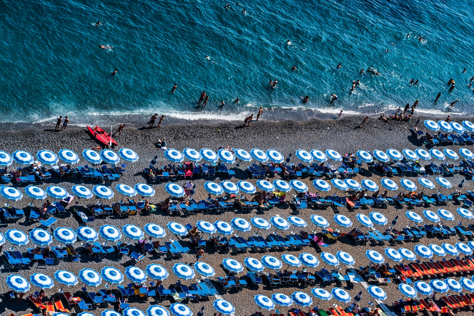 Rows of tightly packed umbrellas line the pebbled shore of Positano