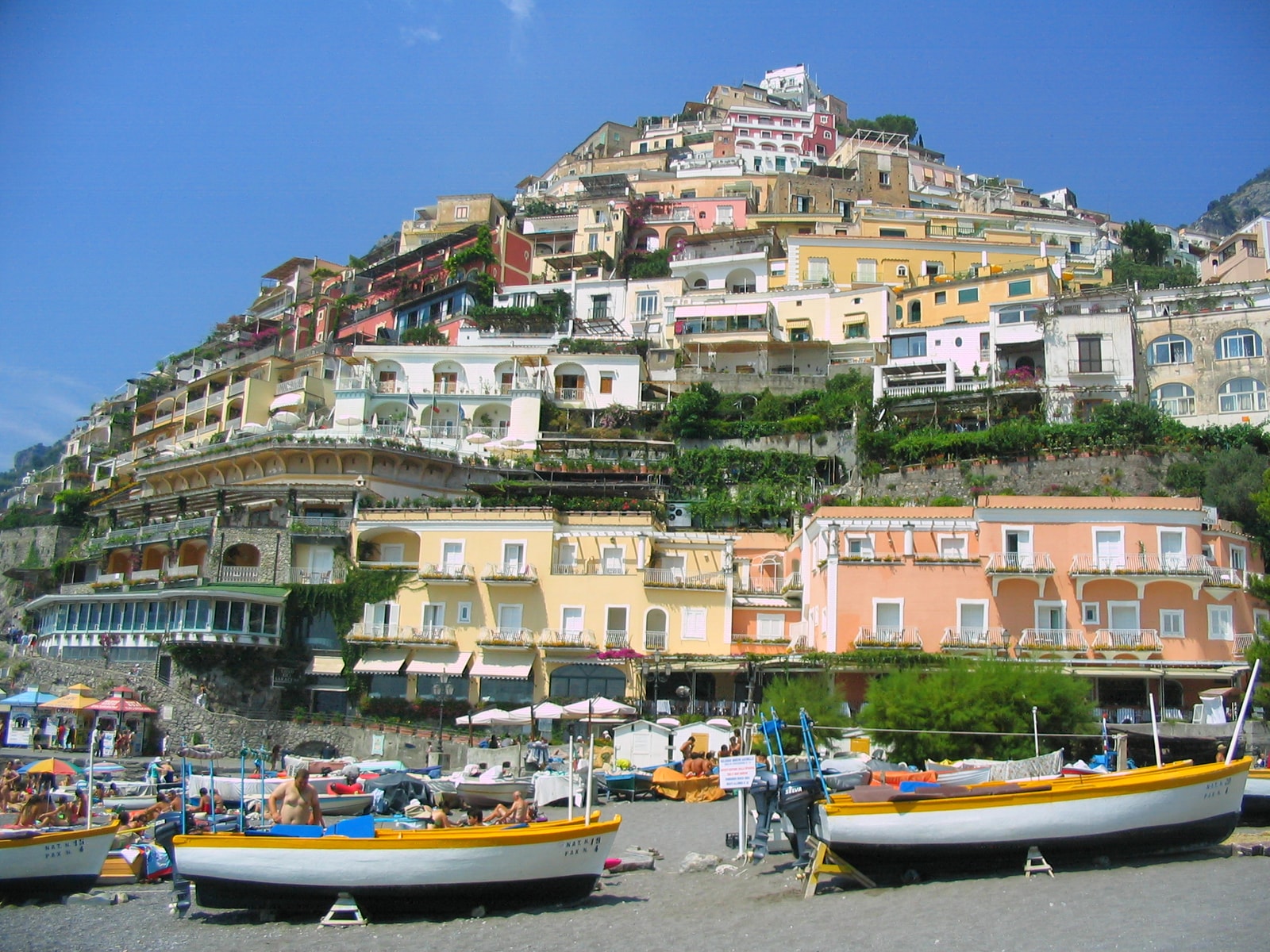 A beach-level perspective of Positano with colorful boats in the foreground.