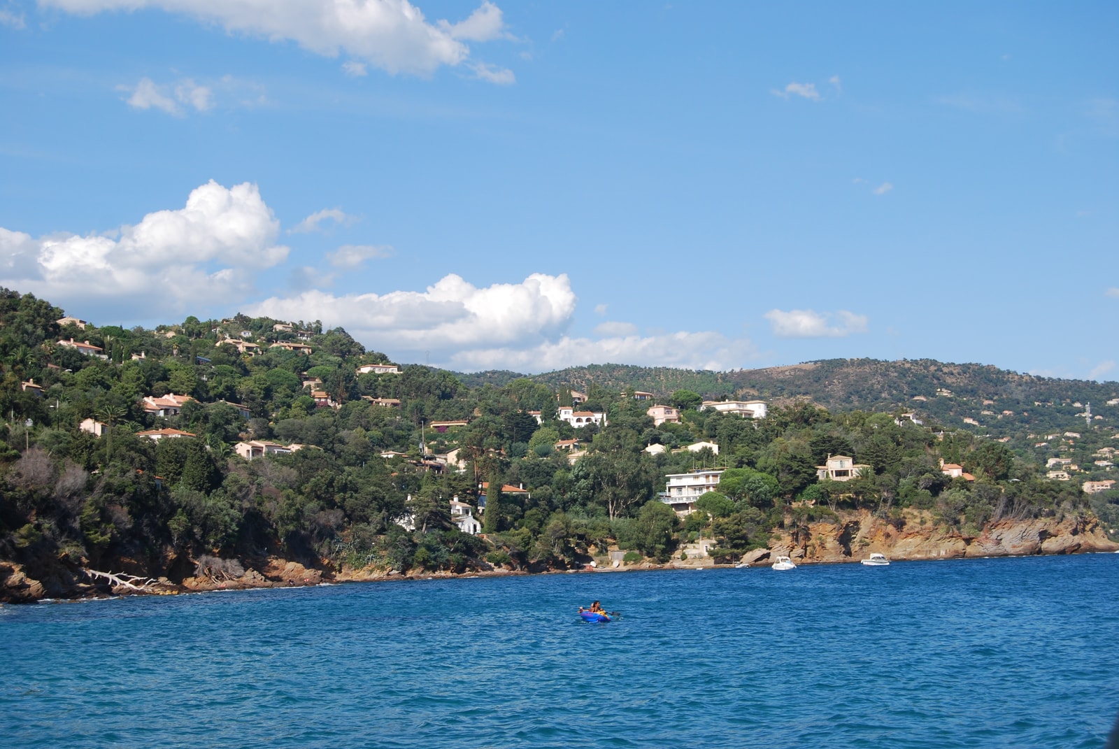 Hillside villas and a coastal boat at Pramousquier.