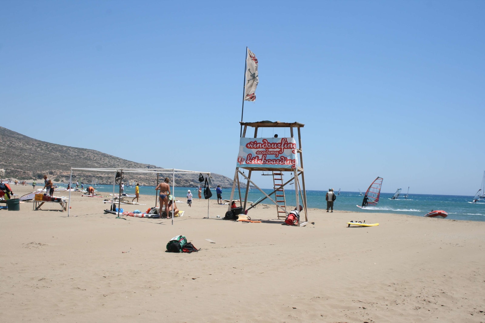 Surfboards and sails are neatly arranged on racks at a surf academy on Prasonisi beach.