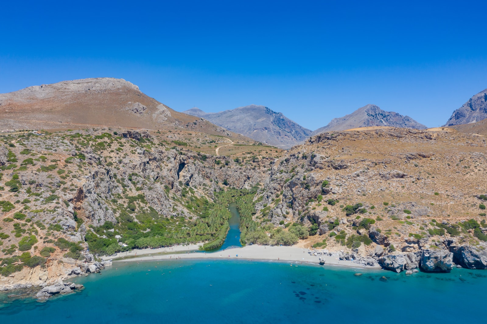 An aerial view shows a river forming a clear route from a gorge to a beach