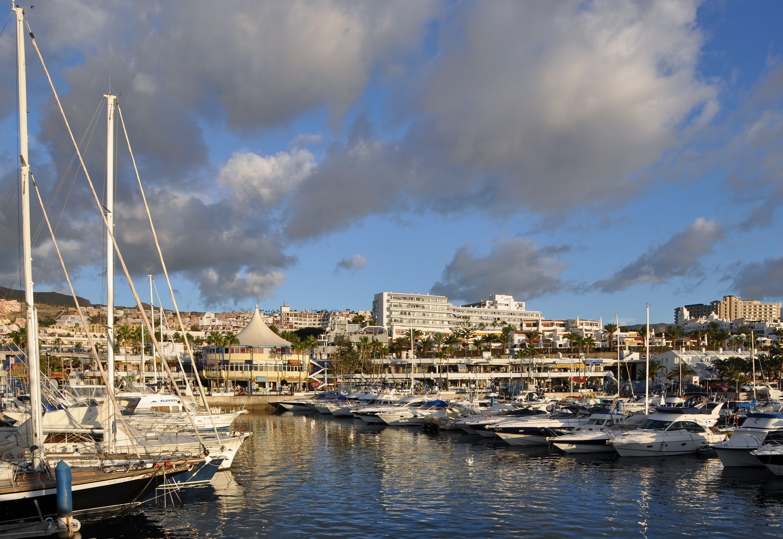 Boats moored in the marina at Puerto Colón, with resort buildings in the background.