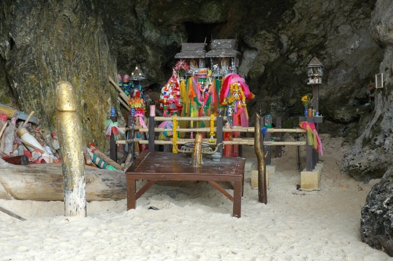 A close-up shot of the shrine at Phra Nang, filled with colorful offerings and symbols.