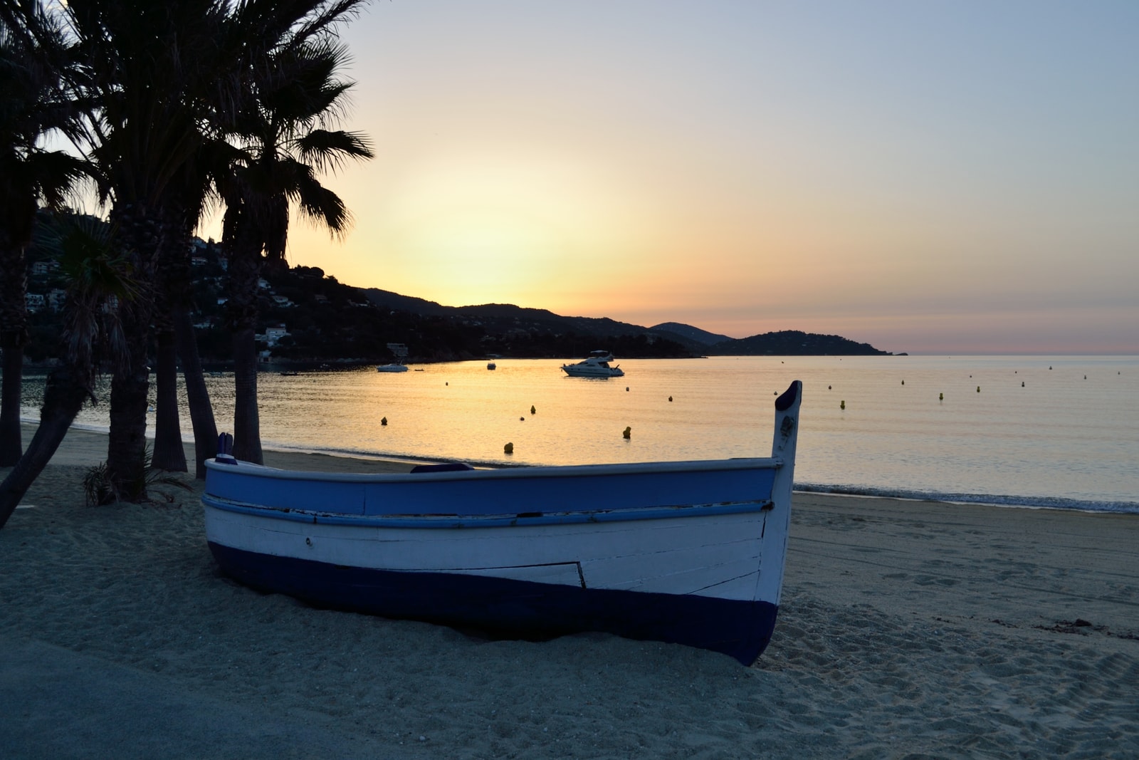 A serene sunset over Saint-Clair Beach with a wooden fishing boat.