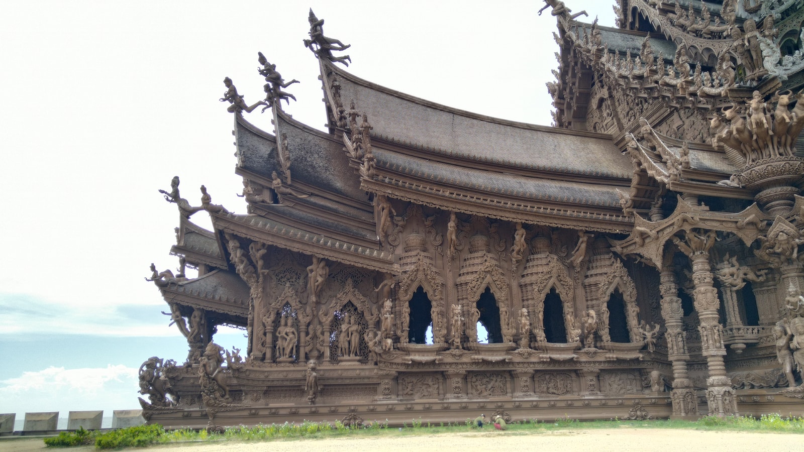 A low-angle shot of the detailed, carved roofline of the Sanctuary of Truth against a blue sky.