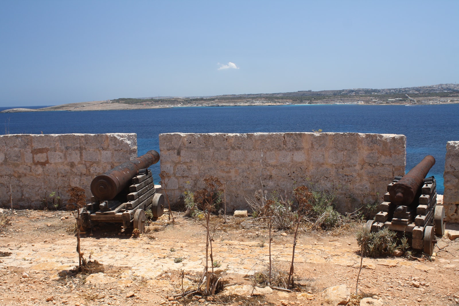 Restored iron cannons positioned at St. Mary's Battery on Comino's coast.