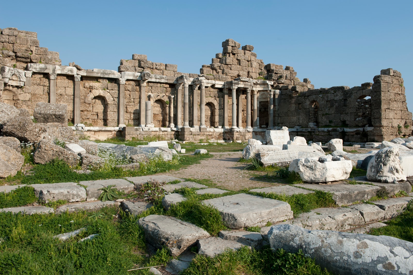 The ruins of the State Agora in Side, with stone columns and arches standing amidst grassy areas.