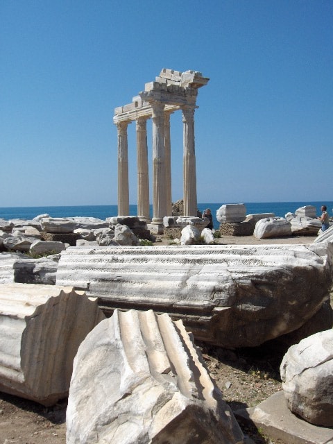 The ancient columns of the Temple of Apollo stand against the blue sky and sea in Side.