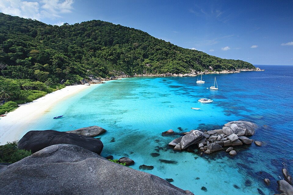 A scenic view of Mu Ko Similan National Park with large granite rocks, bright turquoise shallows, and forested islands.