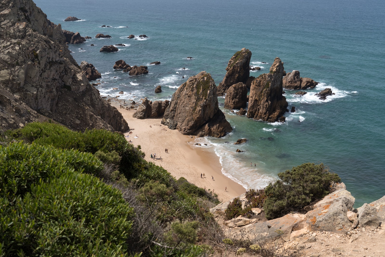 Clear afternoon view of the colossal rock spikes and sheer jagged cliffs of Praia da Ursa