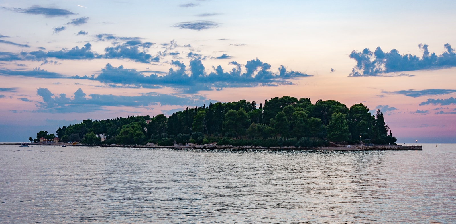 A panoramic seascape of St. Catherine Island at dusk, stretched across the water under soft, pale pink and violet skies.