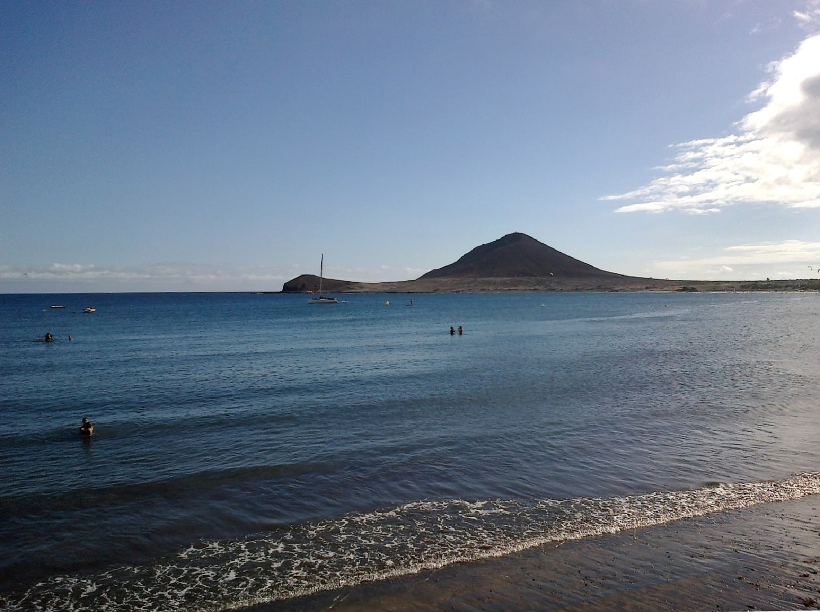 A view across the water at El Médano beach towards the distinctive red volcanic cone of Montaña Roja.