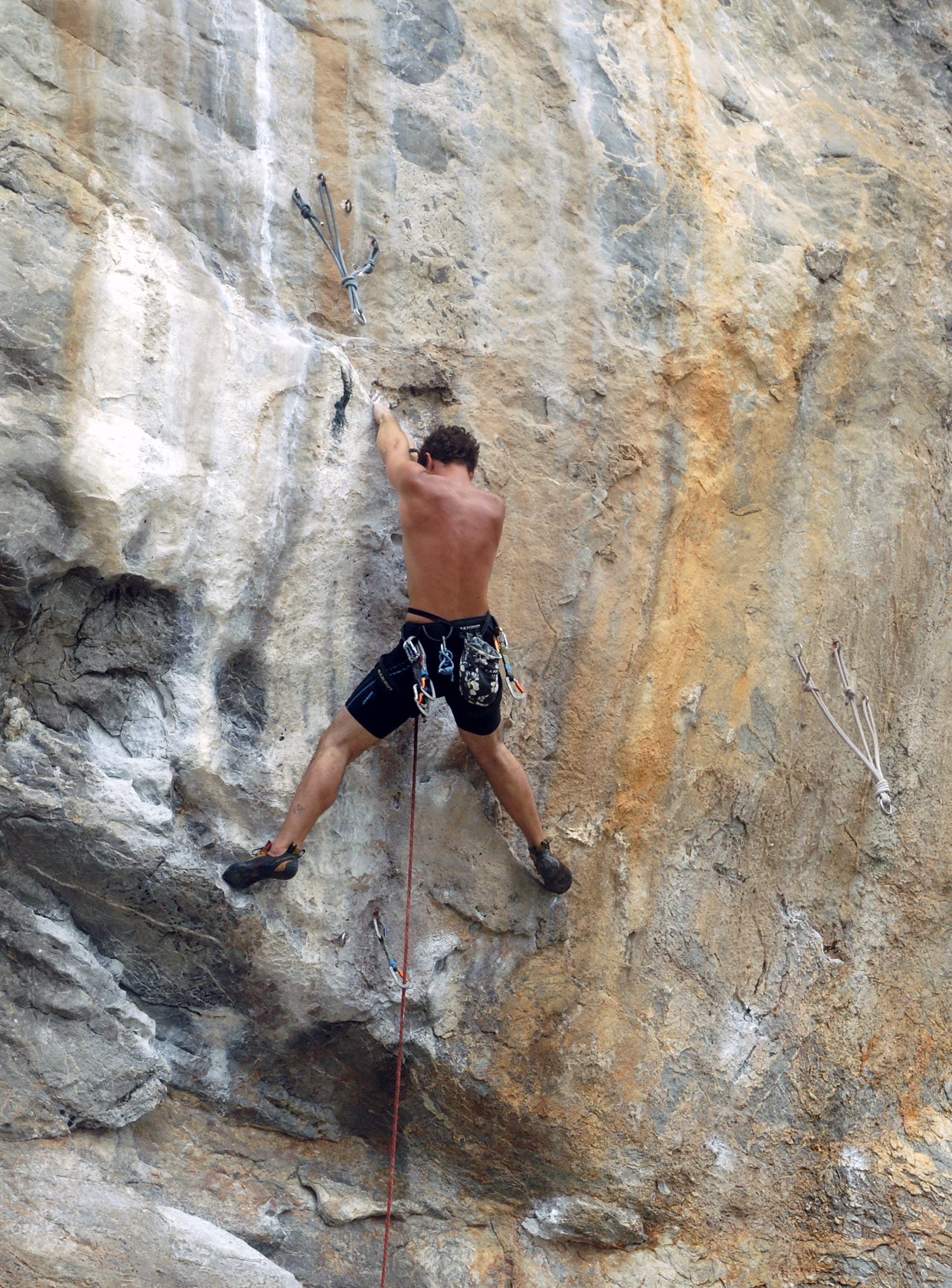 A close-up action shot shows a rock climber gripping the rough, orange-tinted limestone wall at Tonsai Beach.