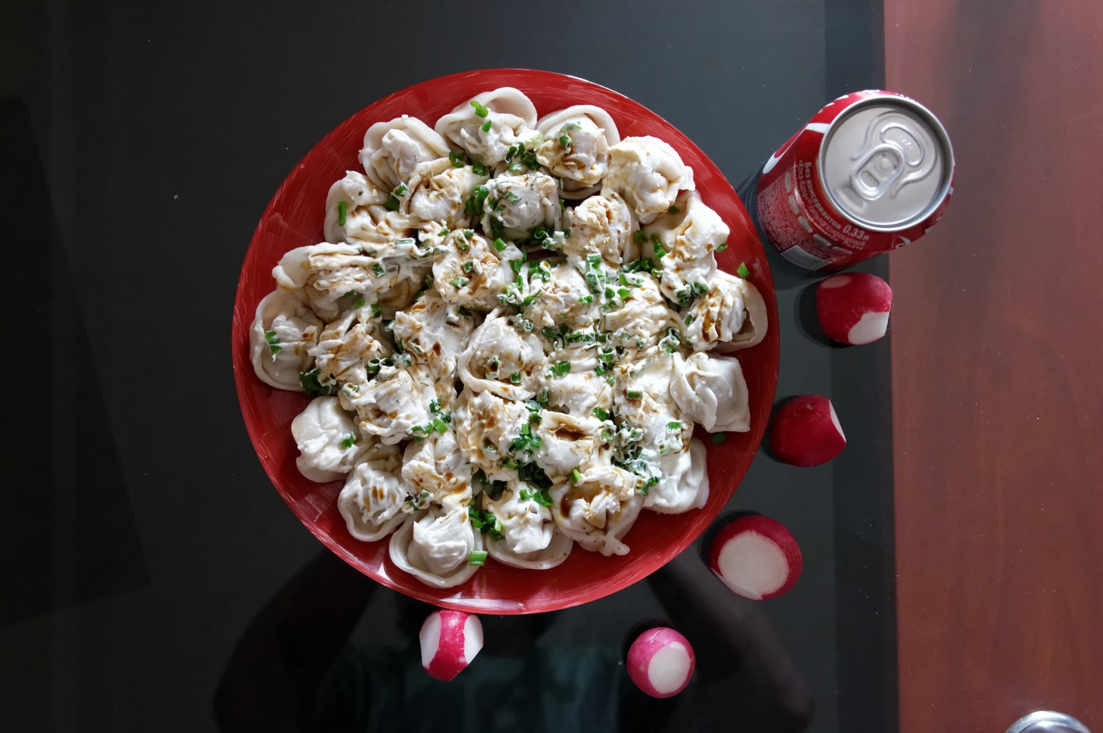 A plate of traditional Russian pelmeni, small meat-filled dumplings, served with sour cream and fresh dill.