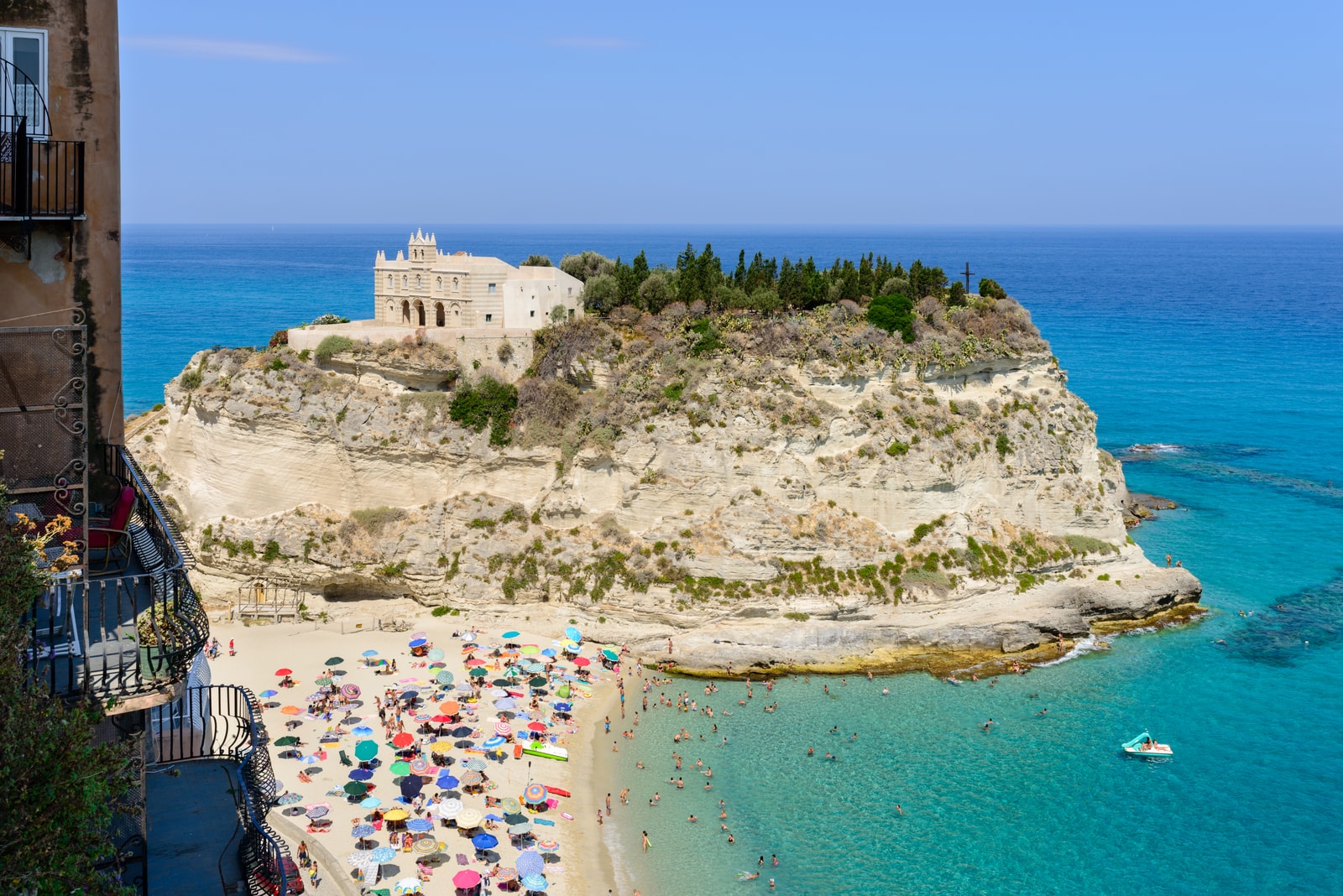 A detailed view of the Benedictine Sanctuary of Santa Maria dell'Isola perched on its sandstone cliff above the sea.