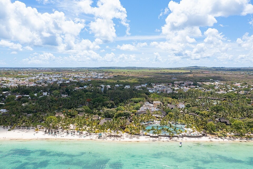 An aerial view of the Trou aux Biches Beachcomber resort, showing its extensive grounds, pools, and location right on the white-sand beach and turquoise lagoon.
