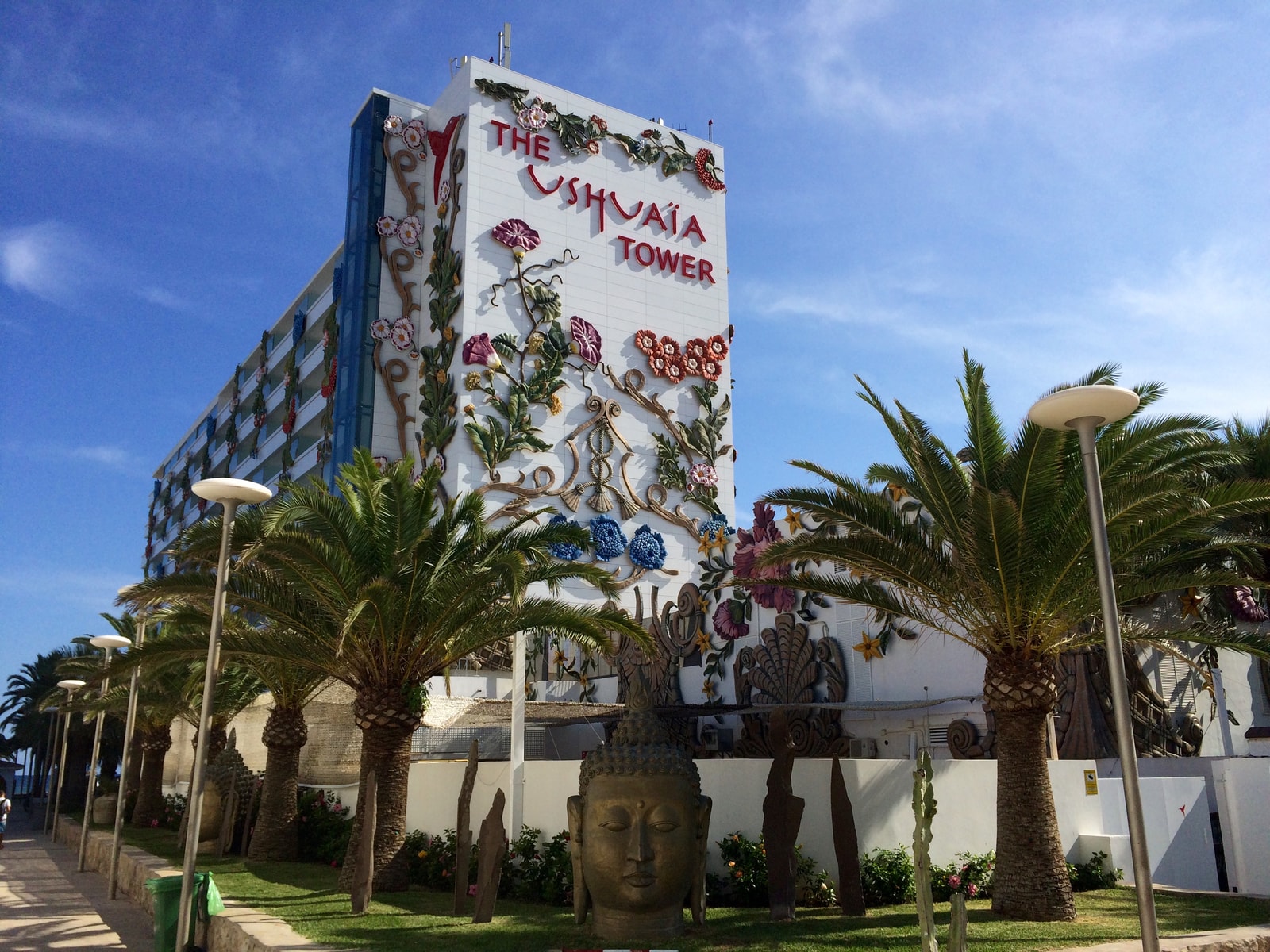 The facade of the Ushuaïa Tower, adorned with colorful floral reliefs and flanked by palm trees.