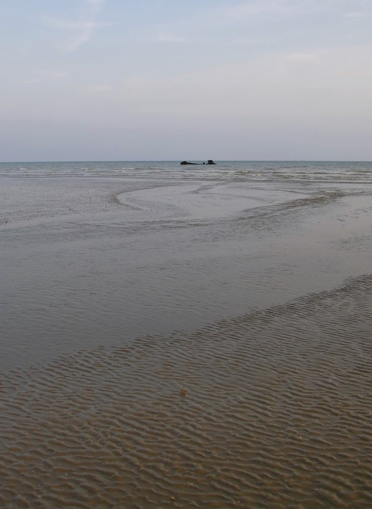 The skeletal wooden remains of a shipwrecked trawler are visible at low tide.