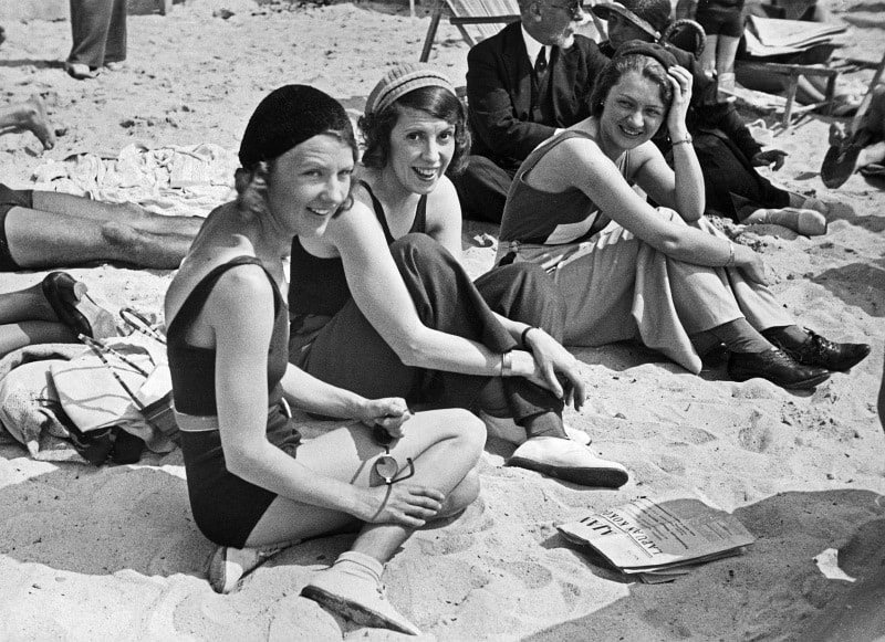 A vintage 1930s photo shows people exercising and relaxing on a sunny beach in Juan-les-Pins.