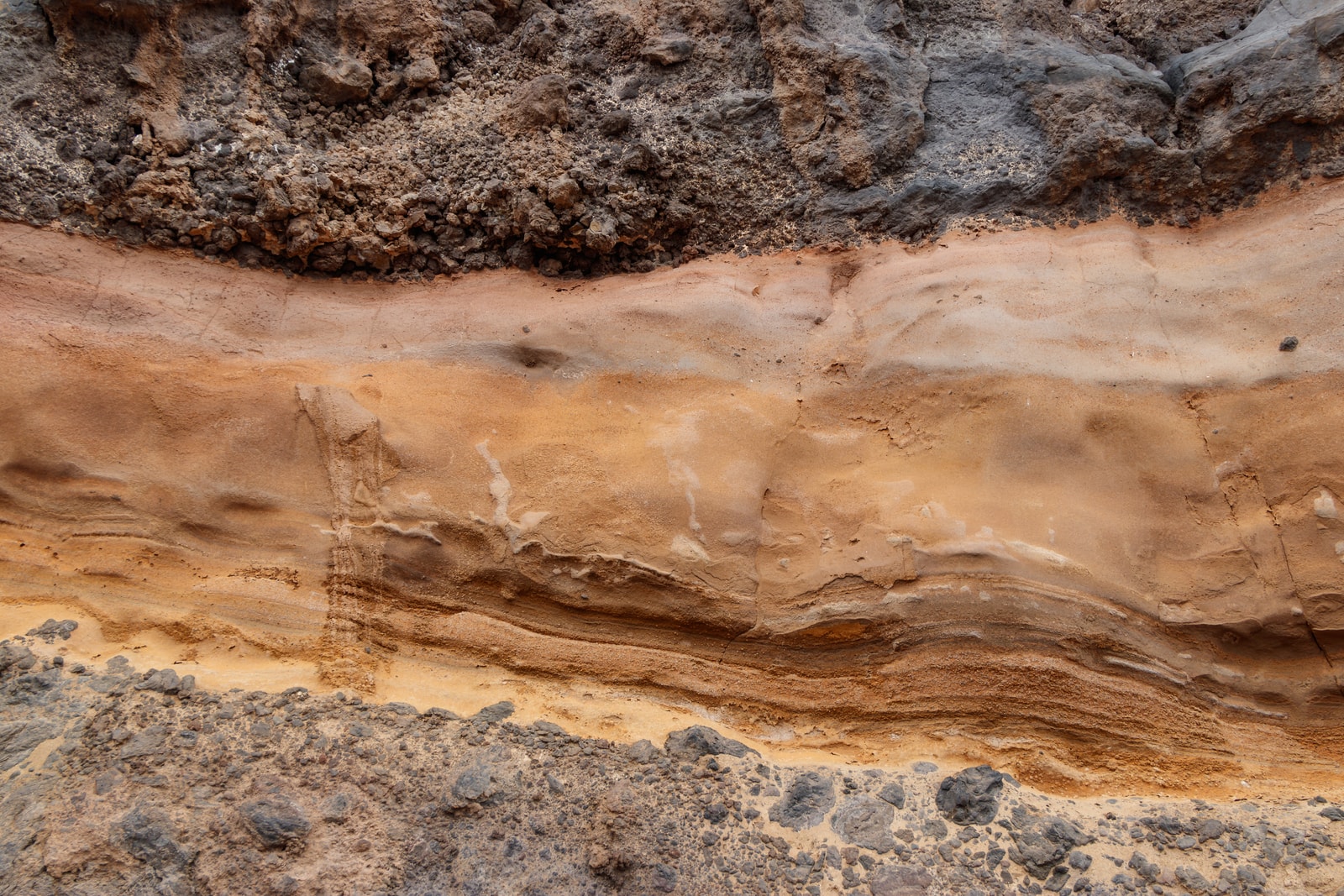 A close-up shot of volcanic rock layers at Playa Santiago, showing the geological detail of the island's coastline.