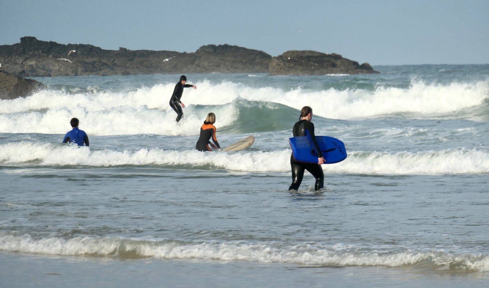 Surfers in wetsuits catch waves at Porthmeor Beach during a crisp Christmas morning session.