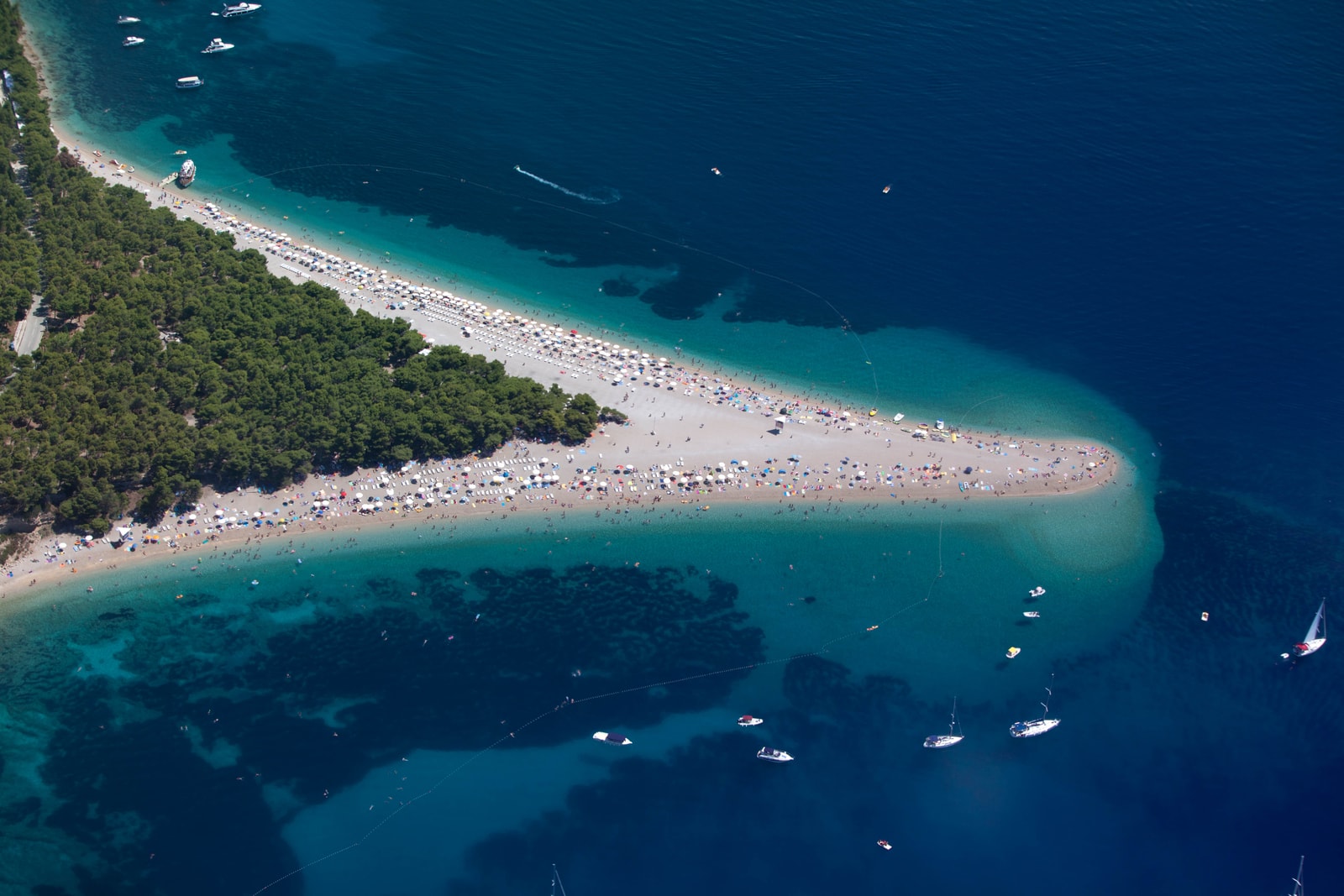 The beach is crowded with sunbathers and colorful umbrellas during the peak summer season.